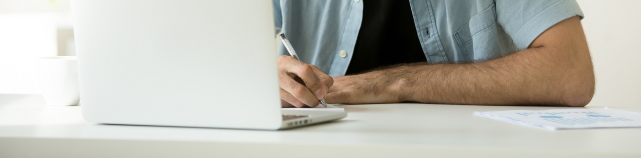 Image of a man with a pen using a laptop