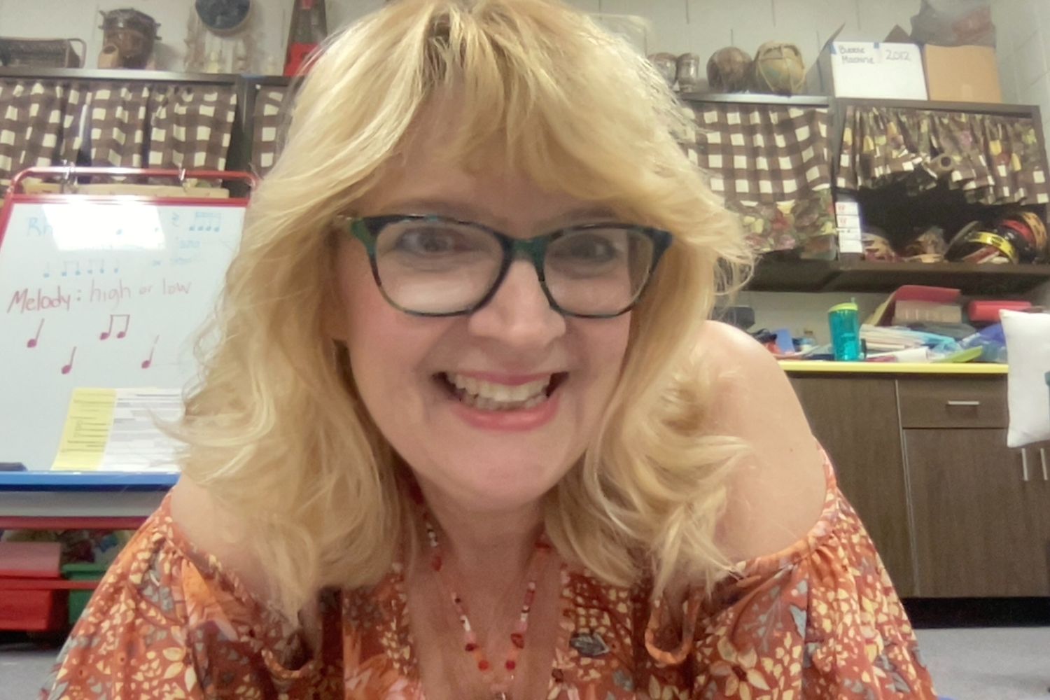 Image of a teacher with blond hair and glasses smiling