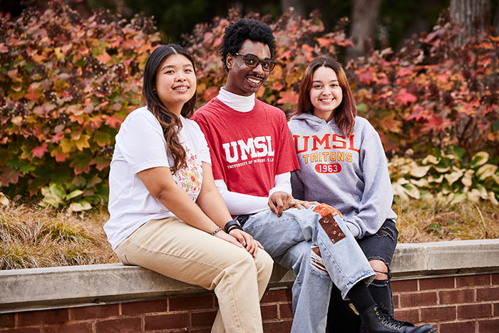 three students sitting on campus in the fall