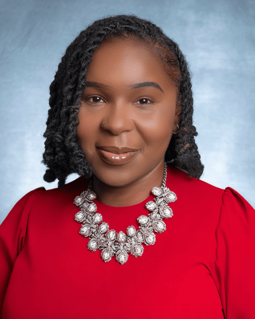 headshot of Ms Logan with a red top and necklace