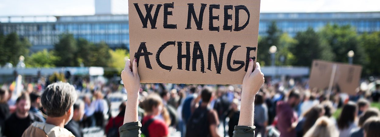 protester holding up a we need change sign