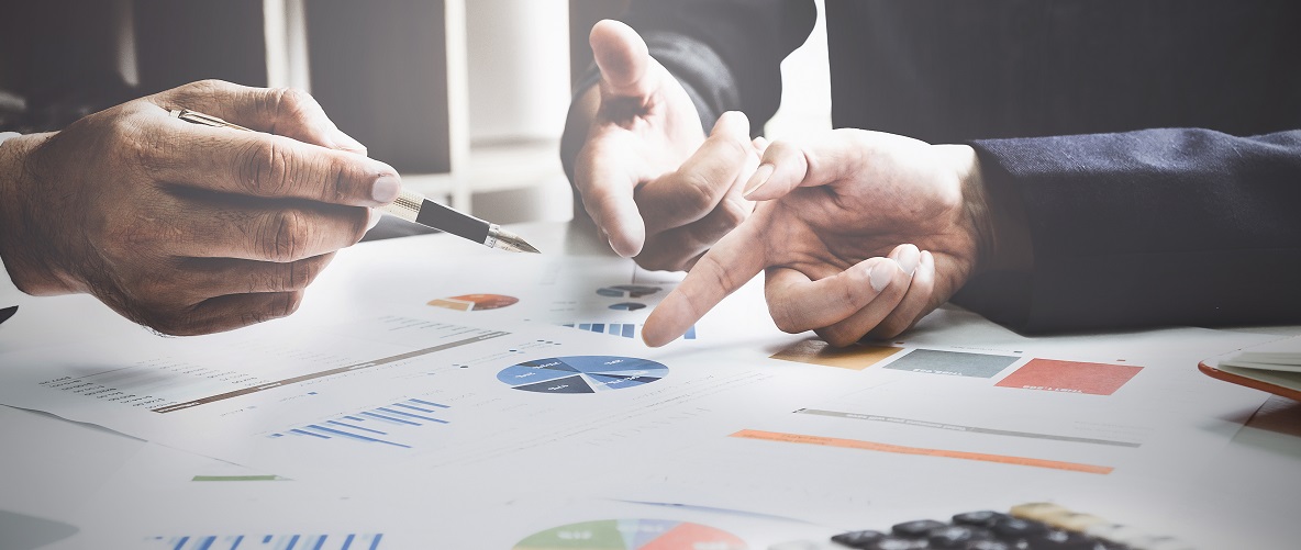 three hands pointing at a pie chart on a piece of paper