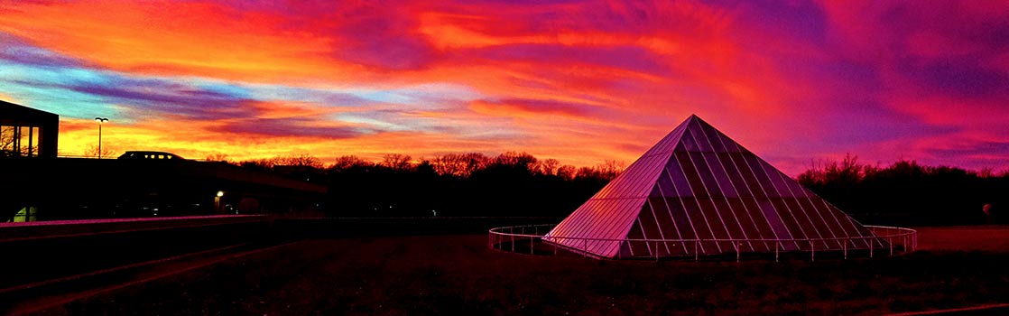 The glass pyramid in front of a vibrant sunset sky