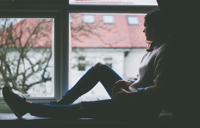 Woman sitting solemnly looking out a window
