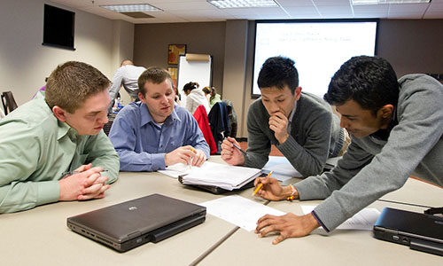 Male students around a table with laptops
