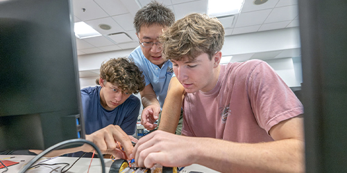 Two students work together on an engineering project with guidance from Dr. Xin Wang