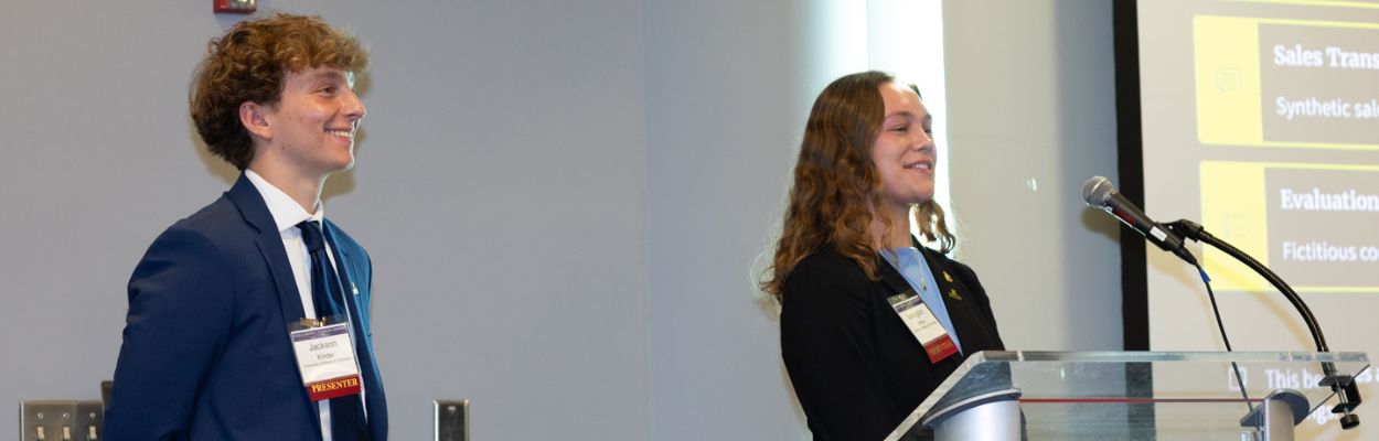 A young man in a business suit and a woman in business suit behind a podium