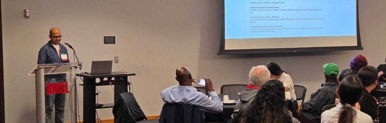 A group of people in a room watching a person present in front of a podium
