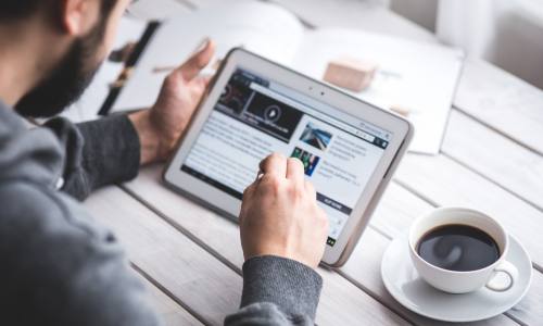 Man scrolling through a web page while using a tablet.