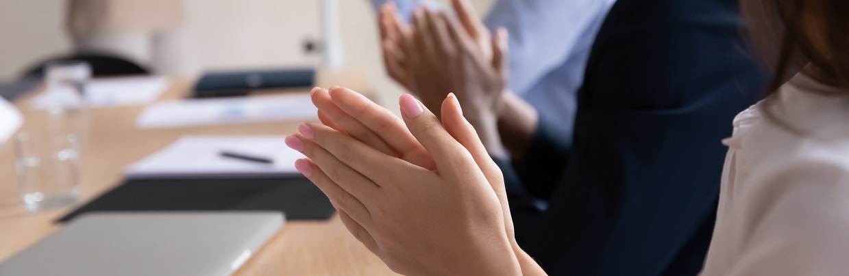 People around a table, close up of hands clapping