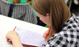 student at a desk writing on a notepad