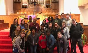 Group photo of a diverse gathering in a church setting, featuring smiling participants on the steps in front of the altar.