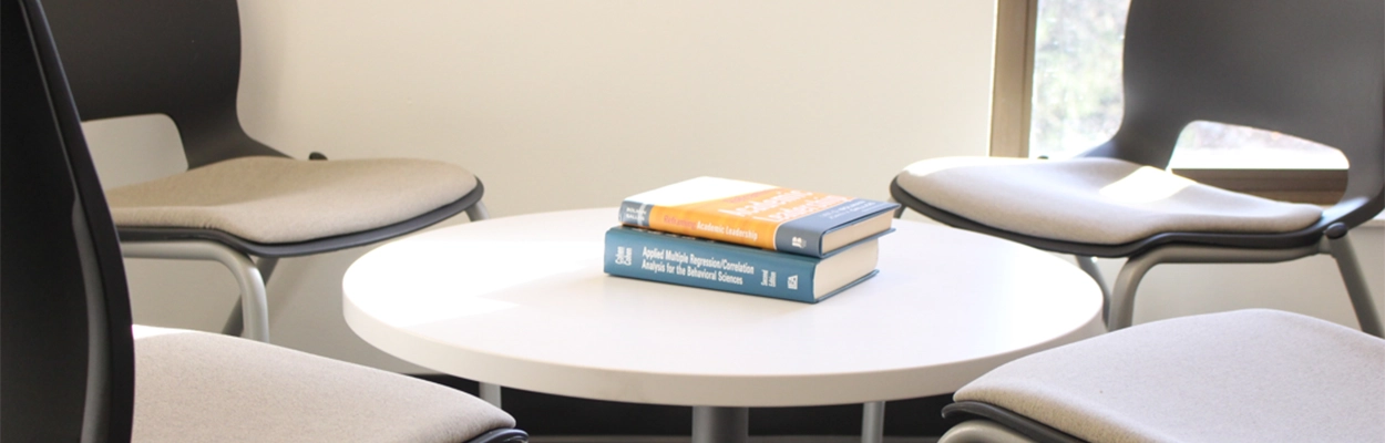 four chairs surrounding a small table with two books on top of said table