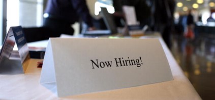 folded card stock on a table that says Now Hiring!