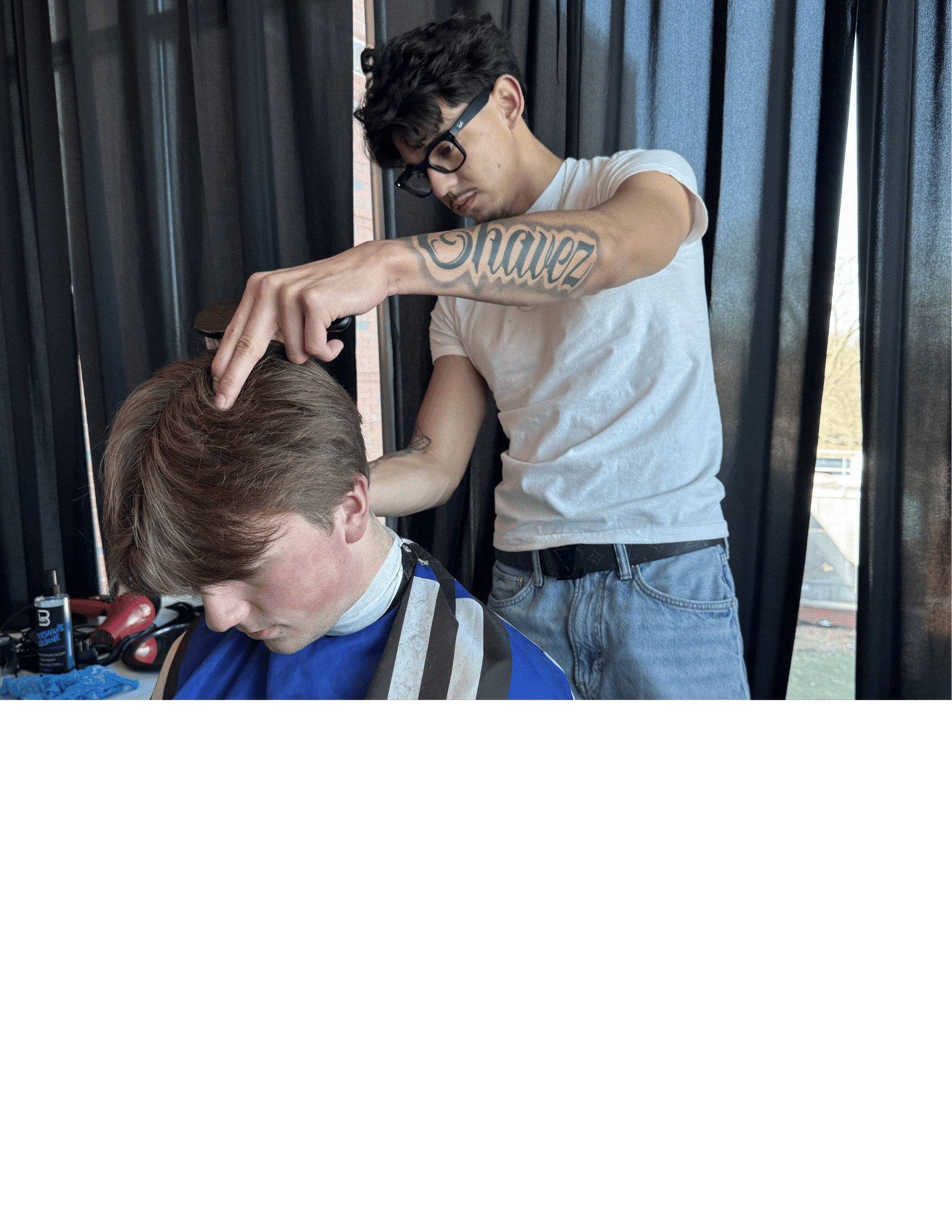 Barber is cutting a student's hair with hair clippers