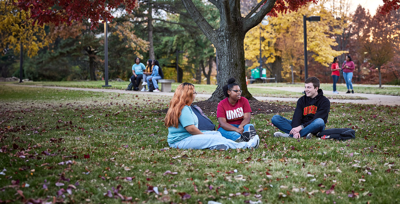 Three students seated outside the TJ Library