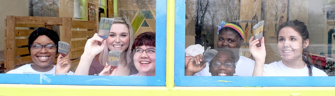 students behind windows painting