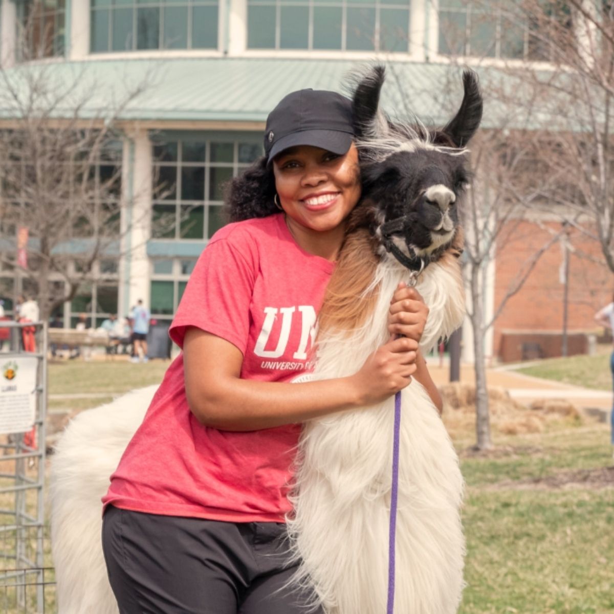 Student posing with brown and white llama