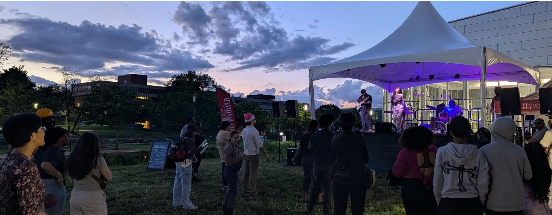 Outdoor concert by the recreation and wellness center. Group of students gathered around a stage to Alysha Paimin.