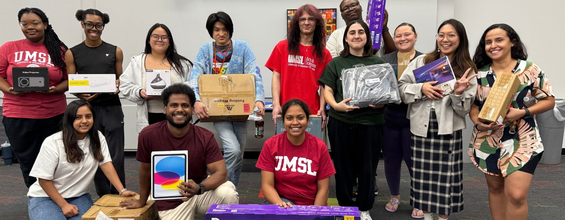 Group of 10 students holding various household prizes from move in bingo