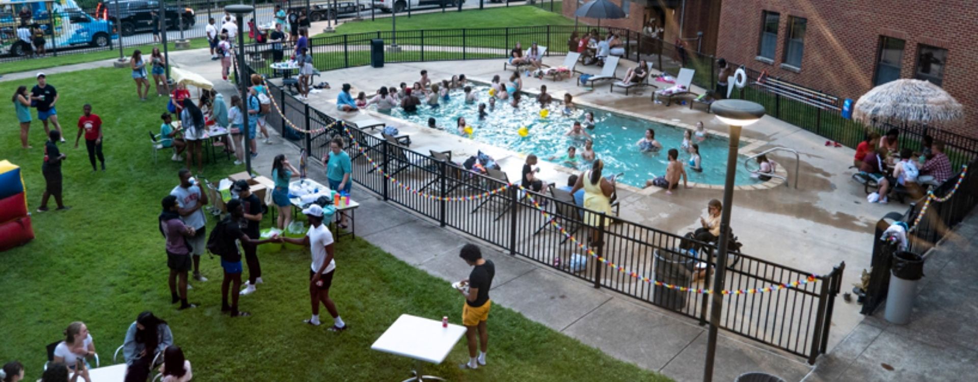 Aerial view of Oak Hall's backyard pool. Student swiming in the pool and enjoying activities on the lawn,