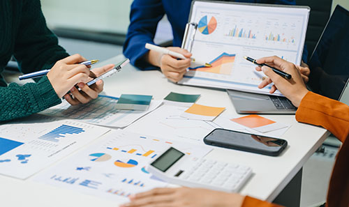 People work around a desk that has pictures of graphs and models.