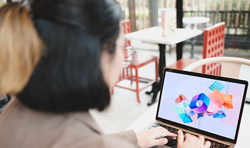A woman sits with a laptop. On the screen is the SharePoint logo.