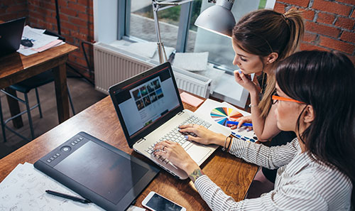 Two women work on a website together. 