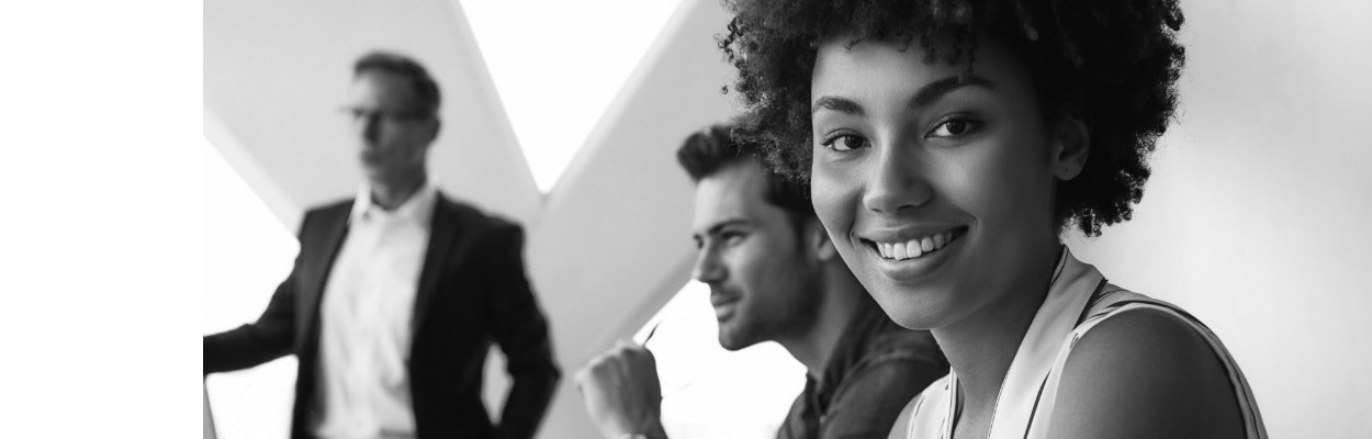 three people in business casual clothing walking up white stairs, a wall of windows to the left