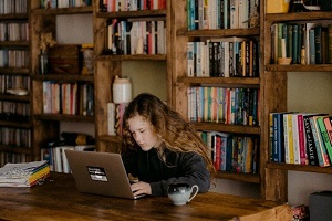 Student sitting at table on the computer learning how to do database querying in SQL