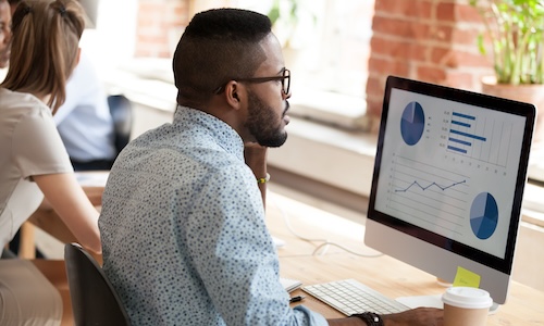 students sitting around table with laptops looking at someone pointing to something on the board that will be put into Tableau