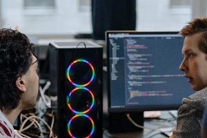 Picture of two people talking about coding with code on computer screen