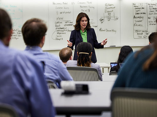 professor at the front of a full classroom