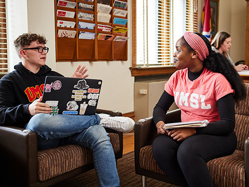 two UMSL students sitting in chairs talking