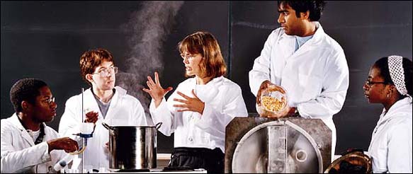 Amy Smith, center, with students and inventions (from left: phase-change incubator, grain mill and sugarcane charcoal).